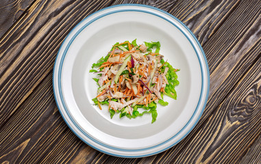 Salad in a plate on wooden background, top view