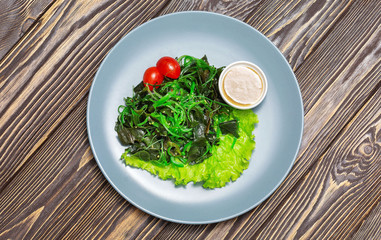 Salad in a plate on wooden background, top view