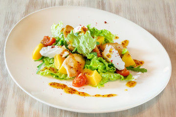 Salad on a white plate on a wooden table