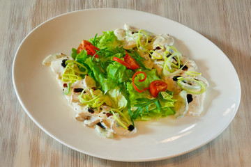 Salad on a white plate on a wooden table