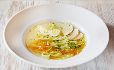 Light soup with chicken and egg in a plate on the table
