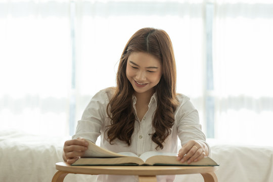 Beautiful Attractive Asian woman sitting on bed in bedroom reading book for learn and education smile and positive thinking feeling so happiness and comfortable,Education Concept