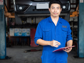 handsome asia man automotive mechanc in garage with copy space