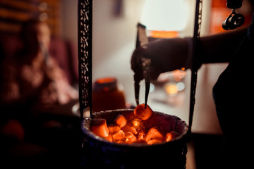 hot red coals for Shisha warmed up on the stove in a hookah bar on a dark background