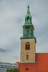 Obraz premium Beautiful tower with a spire and gold ornaments. Red brick roof religious buildings. Old architecture, clock tower. Cityscape.