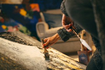 artist painting in her art studio. detail of paint brush