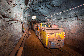 Fototapeta na wymiar Underground gold iron ore mine shaft tunnel gallery passage with light and electric locomotive loco
