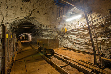 Fototapeta na wymiar Underground gold iron bauxite ore mine shaft tunnel gallery passage with light and wagon