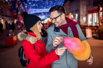 Young couple eating cotton candy and having great time.