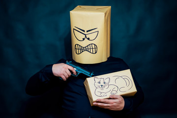 Emotion concept. The man is holding a kitten. Sent the barrel of the gun at him. The expression on...