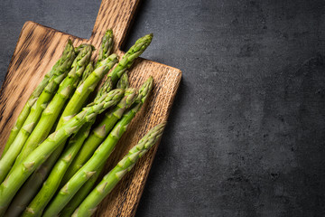 Fresh green asparagus on black slate background.