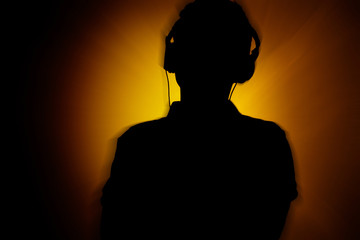 silhouette of teenager in headphones, music lover guy on a disco background with radial blur, concept youth lifestyle