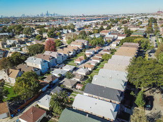 Aerial view traditional residential neighborhood west of Chicago. Row of classic house with garden and detached garage. Skylines from downtown in background