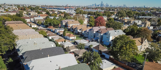 Panorama aerial view traditional residential neighborhood west of Chicago. Row of classic house with garden and detached garage. Skylines from downtown in background