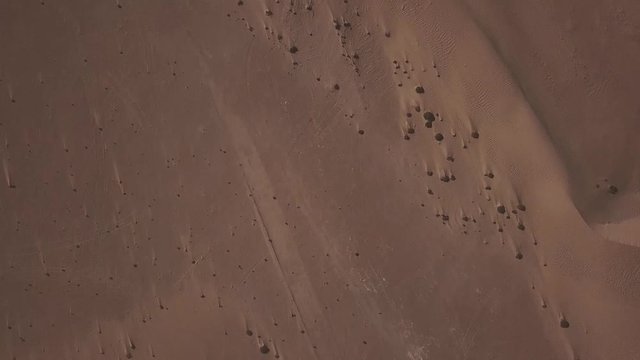 aerial view looking down on desrt and a road cutting throught the sand dunes.