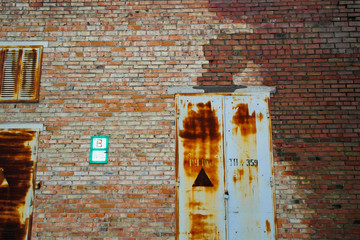 Old rusty doors of technical building. Deep corrosion. Brick building. Brick wall. Rusty door