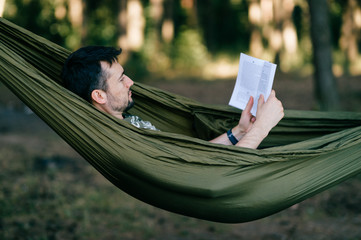 man lies in hammock and reads a book