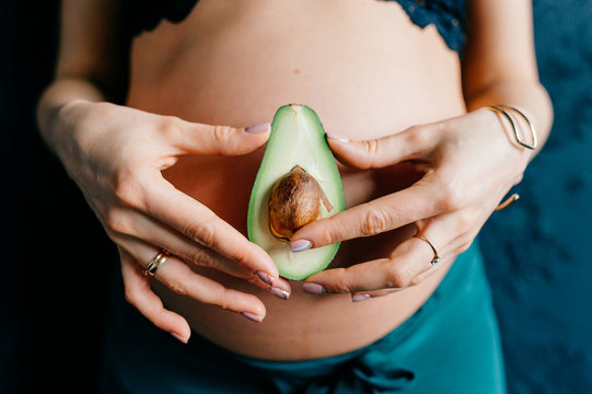 close-up of avocado on background of pregnant belly