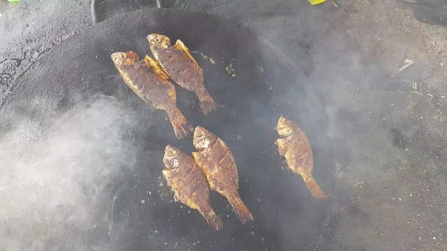 Spicy fish being fried in a big cast iron pan