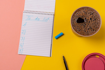 To do list handwritten on a notebook and a cup of hot coffee.