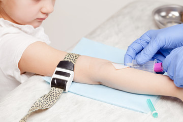 Nurse takes a blood sample from little girls arm - pediatric venipuncture  procedure