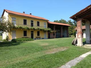 A typical northern Italian yellow farmstead, with a green lawn yard, an ivy covered balcony and a cotto brick warehouse, Bellinzago, Piedmont, Italy