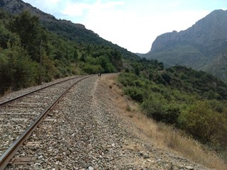 Fototapeta premium Curved rails over a hill among rocky mountains during a sunny summer day in La Peña, Aragon Region, Spain