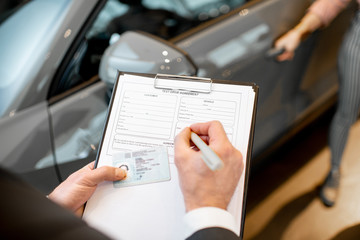 Manager filling test drive documents in the showroom, close-up view