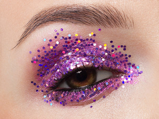 Close eye with colorful eyeshadow. Macro shot of opened human female eye. Woman with evening beauty...
