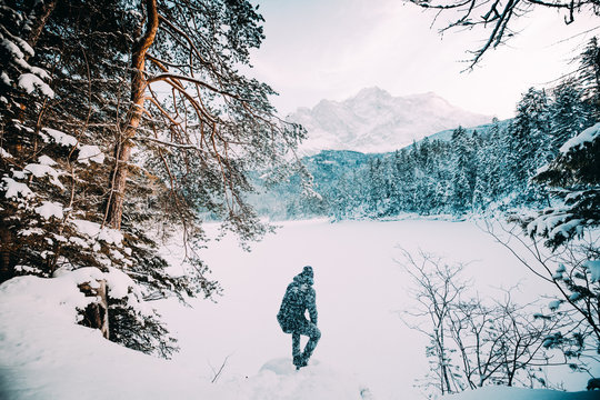 Man between snow field near forest and mountain