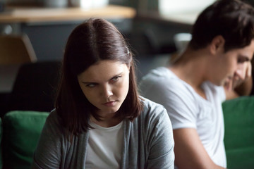 Young male and woman sitting on sofa and not talking, not looking of each other after quarreling at...