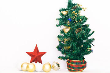 Green, red and gold Christmas tree decorated next to Christmas balls and a red star in front of a white background