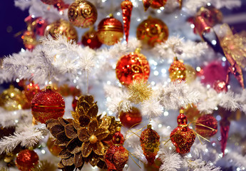 Fototapeta na wymiar Branch of white artificial Christmas tree decorated with gold and red balls. Close up.