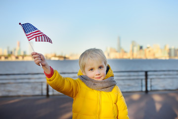 Little boy holding the American flag on the background skyscrapers of Manhattan.