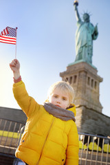 Little boy with American flag on the background of the statue of liberty in the same pose. Travel with kids. © Maria Sbytova