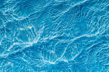 Background of rippled pattern of clean water in a blue swimming pool