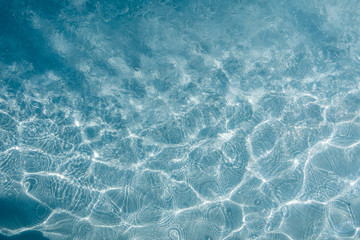 Background of rippled pattern of clean water in a blue swimming pool.