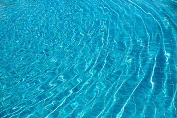 Background of rippled pattern of clean water in a blue swimming pool.