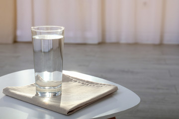 Glass of water on table against blurred background. Space for text
