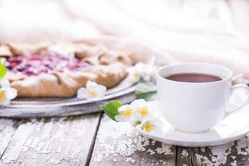 Sweet delicious freshly baked homemade French Country Pie with berries with cup of black tea on a wooden background,