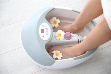 Woman with beautiful legs using foot bath at home, closeup. Spa treatment