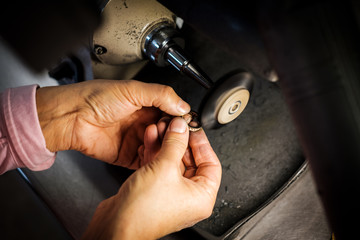 Jeweler polishes gold ring on bench grinder in jewellers workshop