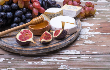 Natural organic fruits - grape, homemade cheese, honey on a wooden table with place for text.