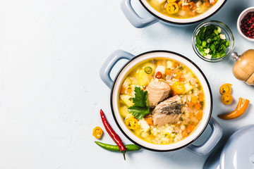 Fish soup with salmon, vegetables and couscous in blue pots. Top view, space for text.