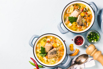 Fish soup with salmon, vegetables and couscous in blue pots. Top view, space for text.