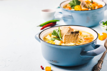Fish soup with salmon, vegetables and couscous in blue pots. Selective focus, space for text.