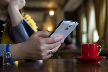 Close up of women's hands holding cell telephone with blank copy space screen for your advertising text message or promotional content, girl watching video on mobile phone during coffee break