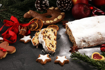 Traditional European Christmas pastry, fragrant home baked stollen, with spices and dried fruit. Sliced on rustic table with xmas tree branches and decorations