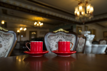 Close up of women's hands holding a red cup of coffee in the cafe concept.