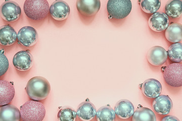 Christmas pink and silver baubles as frame on pastel pink background. Top view with space for text.